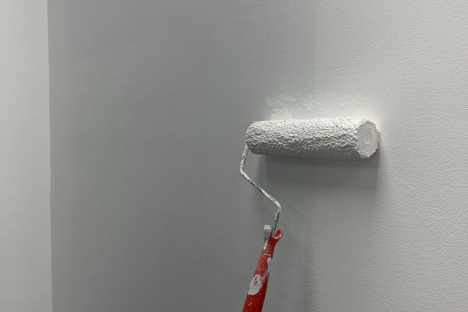 After: Freshly painted white wall with a paint roller