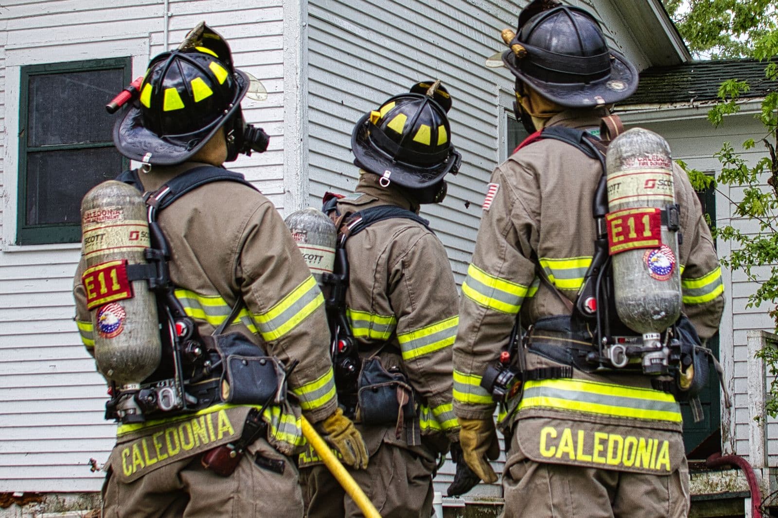 Firefighters in gear outside a house after a fire